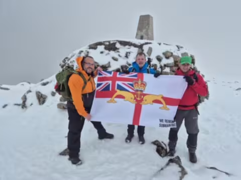 Three Peaks team at snowy summit with WRS ensign